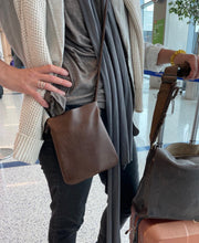 Load image into Gallery viewer, woman stands wearing x-small distressed brown leather crossbody bag. its bottom corners are rounded. This bag is artisan made and handcrafted.
