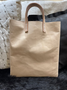 natural vegetable tanned leather bags small size, narrow-rectangular flat shape. two veg tan handles attached/sewn using belgian linen yarn. also made in distressed brown & black leather and black & tan suede. Retail price $195.