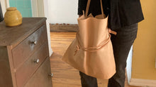 Load image into Gallery viewer, Close up of natural vegetable tanned leather bag (with a light patina). Drawstring style— veg tan leather ties that cinch in for closure or remove ties to wear without. Made with knotted/adjustable crossbody length straps.
