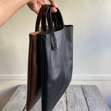 Load image into Gallery viewer, Black and brown leather bags small size, narrow-rectangular flat shape. two veg tan handles attached/sewn using belgian linen yarn. also made in natural vegetable tanned leather and black &amp; tan suede. Retail price $195.
